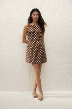 Woman wearing a brown polka dot dress against a white background