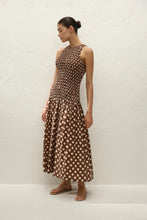 Woman wearing a brown polka dot dress against a white background