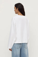 Person wearing a white long-sleeve shirt and blue jeans on a plain background