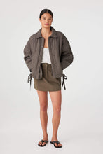 Woman wearing a plaid jacket and green skirt on a white background