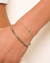 Silver bracelet on a wrist with a plain background