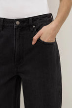 Person wearing black pants with a plain background