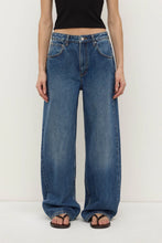 Person wearing blue jeans and a black top on a white background