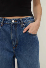 Person wearing blue jeans with a plain background