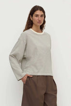 Woman wearing a striped sweater and brown pants against a white background