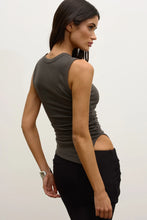 Woman wearing a gray tank top and black pants against a plain background