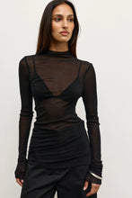 Woman wearing a black outfit with sheer panels on a white background