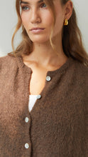 Woman wearing a brown cardigan with a neutral background