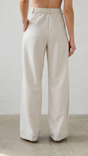 Beige wide-leg pants worn by a person against a plain background