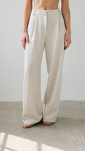 Beige wide-leg pants worn by a person on a neutral background