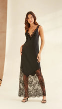Woman wearing a black slip dress with lace details on a neutral background