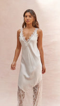 Woman wearing a white lace nightgown against a soft pink background
