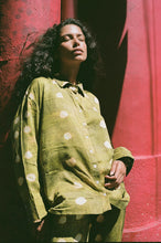 Woman wearing a green polka dot shirt against a red background