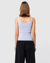 Person wearing a light blue tank top and black pants on a plain background