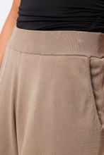 Close-up of beige pants with a black top worn by a person