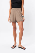 Person wearing a beige skirt and black top on a white background