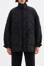 Black quilted jacket worn by a person on a white background