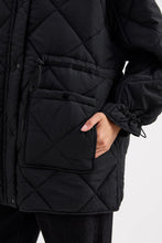 Black quilted jacket with a hand in a pocket on a white background