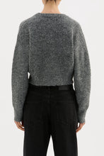 Person wearing a gray knitted sweater and black pants on a white background