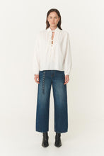 Person wearing a white blouse and blue jeans on a white background
