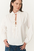 Woman wearing a white blouse with lace-up front design on a white background