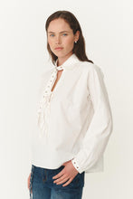 Woman wearing a white blouse with long sleeves on a plain background