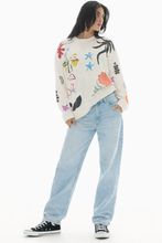 Person wearing a colorful sweater and light blue jeans on a white background